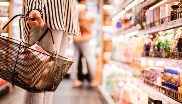 woman shopping in a grocery store aisle, closeup of basket